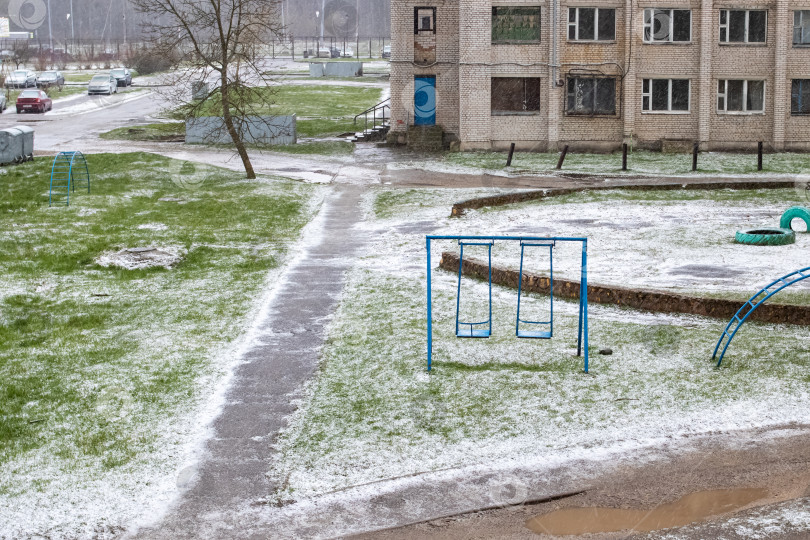 Скачать Пешеходная дорожка, зеленая трава и качели под снегом фотосток Ozero