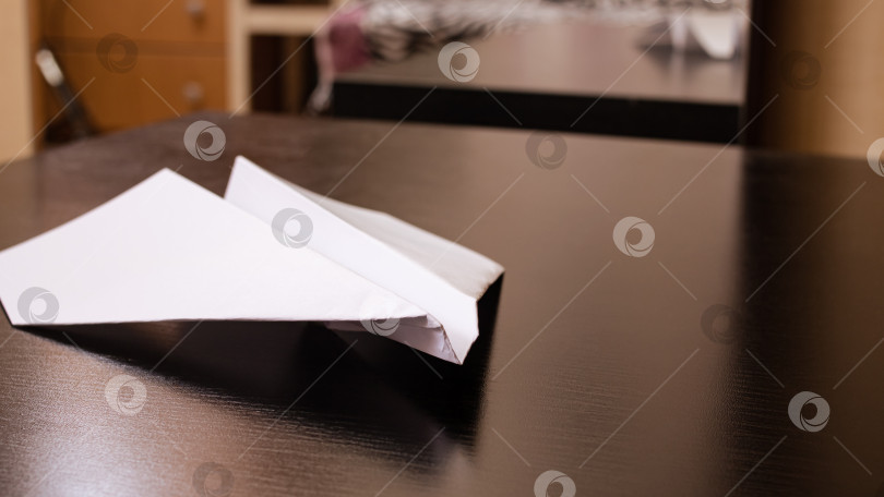 Скачать Белый бумажный самолетик на черном деревянном столе фотосток Ozero
