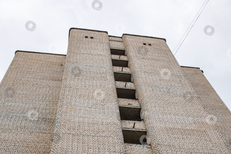 Скачать Старое высокое кирпичное здание, вид снизу на фоне серого неба фотосток Ozero