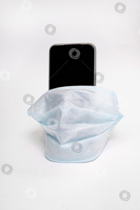 Скачать Мобильный телефон в медицинской маске на сером фоне фотосток Ozero