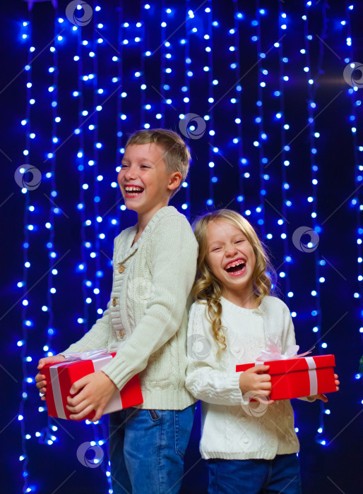 Скачать маленькие дети в костюмах держат коробки с подарками. новый год. счастливого Рождества. Смеяться. На фоне голубых новогодних огней фотосток Ozero