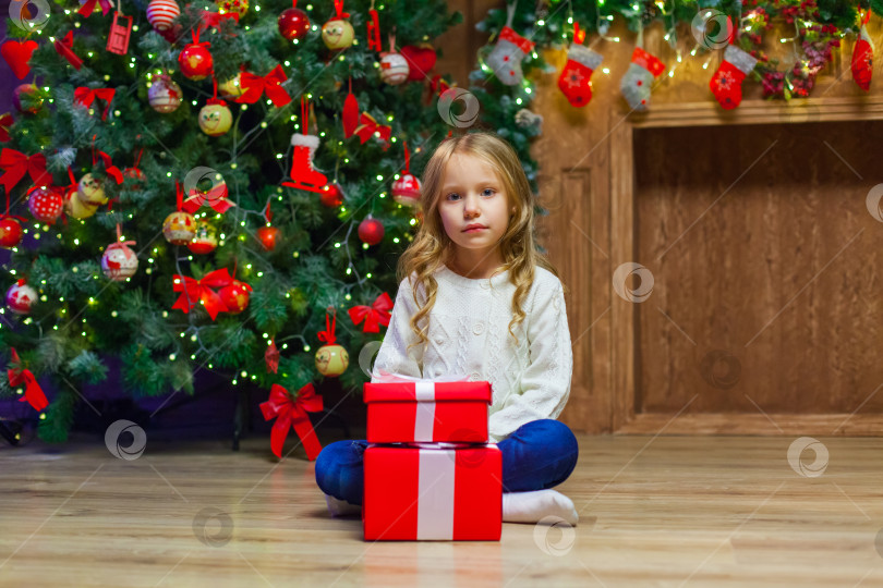 Скачать Счастливая маленькая улыбающаяся девочка с рождественской подарочной коробкой. фотосток Ozero