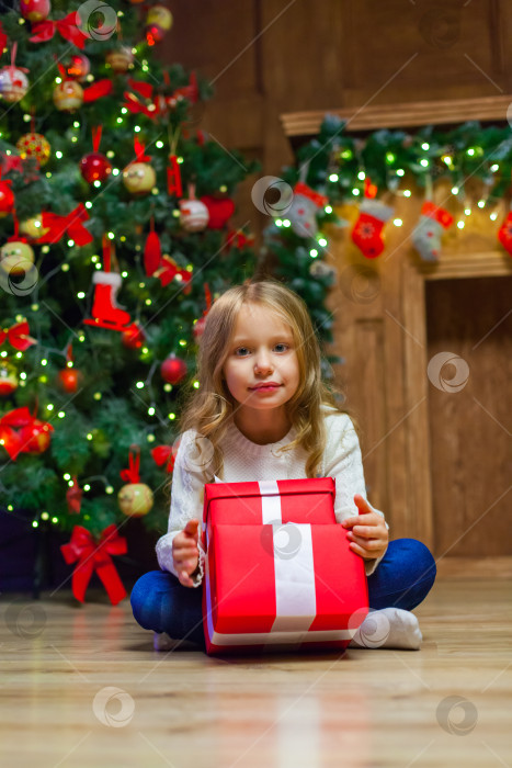 Скачать Счастливая маленькая улыбающаяся девочка с рождественской подарочной коробкой. фотосток Ozero