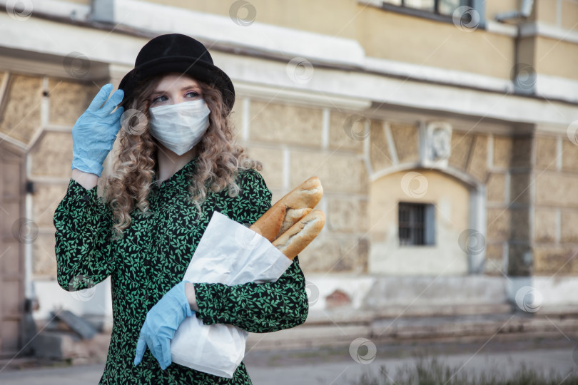 Скачать Женщина во французском стиле в медицинской маске и перчатках с багетом в руках фотосток Ozero