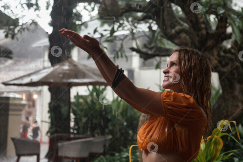 Скачать Молодая женщина в мокрой одежде счастлива под тропическим дождем фотосток Ozero