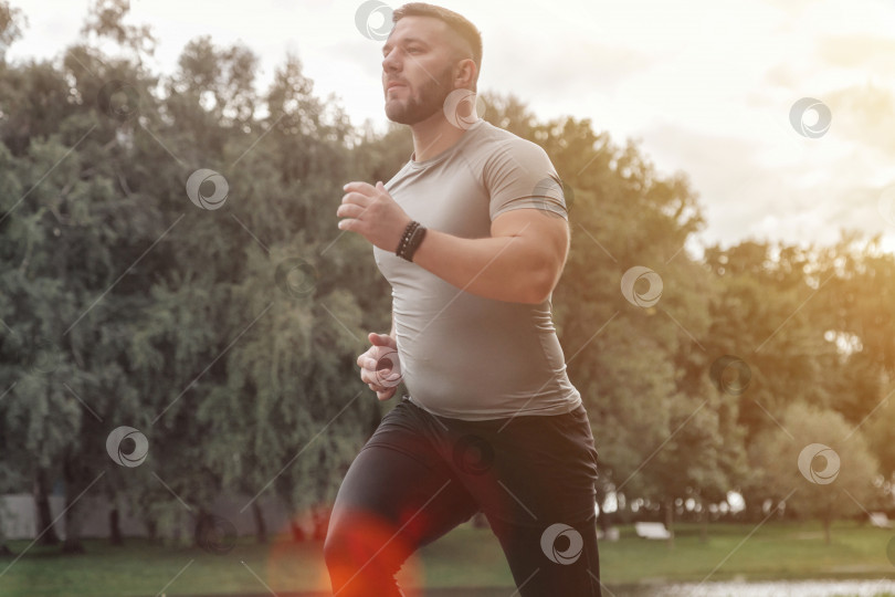 Скачать Мужчина спортсмен бегун, бегущий в парке, тренирующийся и осуществляющий физические упражнения фотосток Ozero