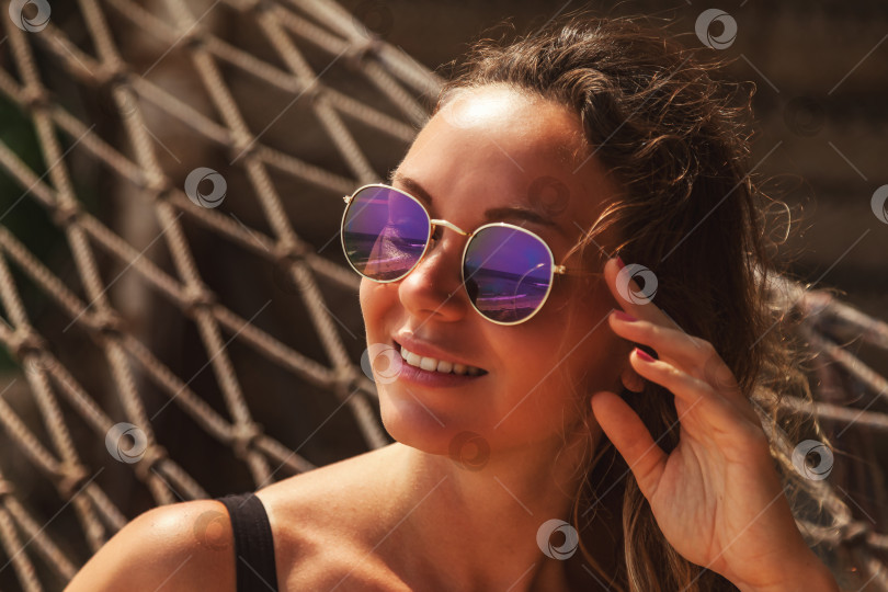 Скачать Женское лицо в солнцезащитных очках, отдыхающее на песчаном тропическом пляже в гамаке фотосток Ozero