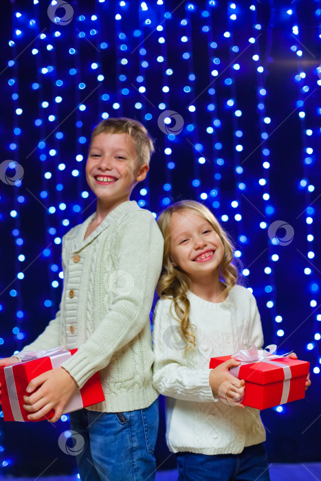 Скачать маленькие дети в костюмах держат коробки с подарками. новый год. счастливого Рождества. Смеяться. На фоне голубых новогодних огней фотосток Ozero