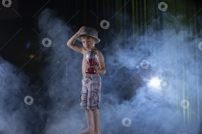 Скачать Маленький мальчик-циркач выступает на фоне освещения сцены. фотосток Ozero