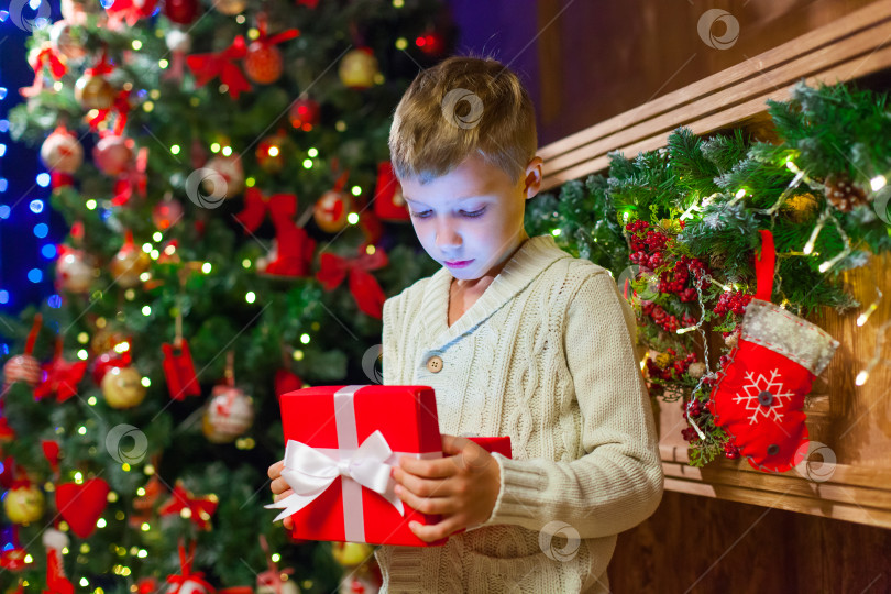 Скачать мальчик с Рождественским подарком Открывает Рождественский Подарок Перед Елкой фотосток Ozero