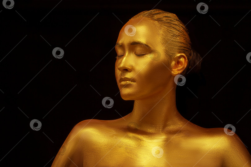 Скачать Девушка-модель с золотистым профессиональным художественным макияжем на черном фоне. Красивое золотисто-металлическое тело, губы и кожа фотосток Ozero