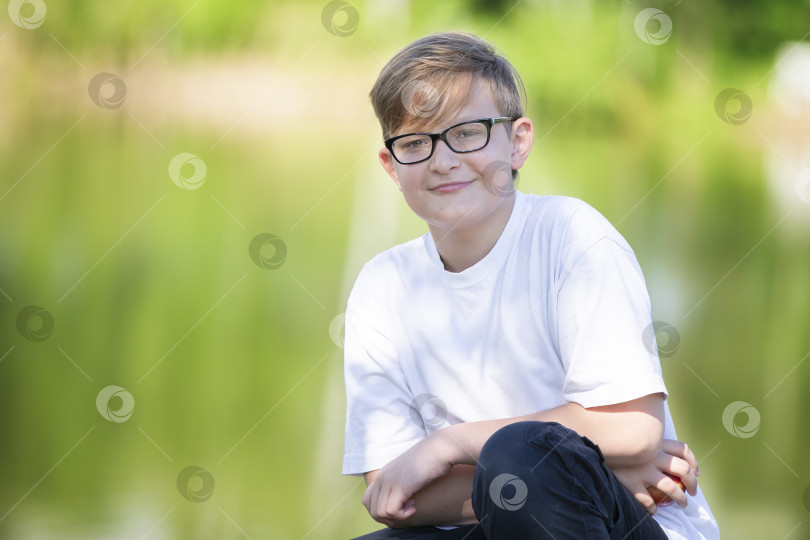Скачать Красивый интеллигентный мальчик в очках смотрит в камеру и улыбается. фотосток Ozero