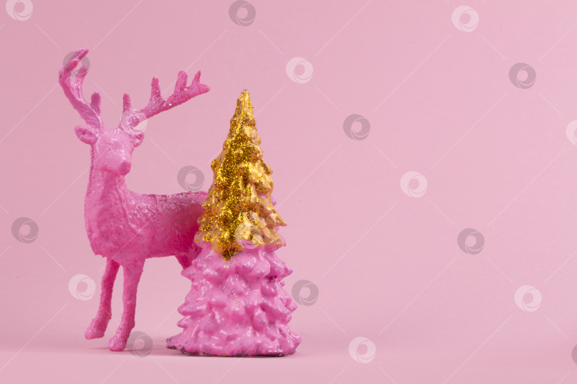 Скачать Праздничный минималистичный рождественский фон. На розовом фоне изображен розовый олень и позолоченная рождественская елка. фотосток Ozero
