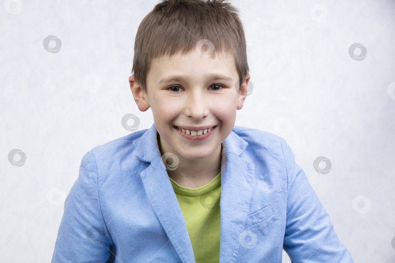 Скачать Красивый мальчик в синей куртке улыбается и смотрит в камеру. фотосток Ozero