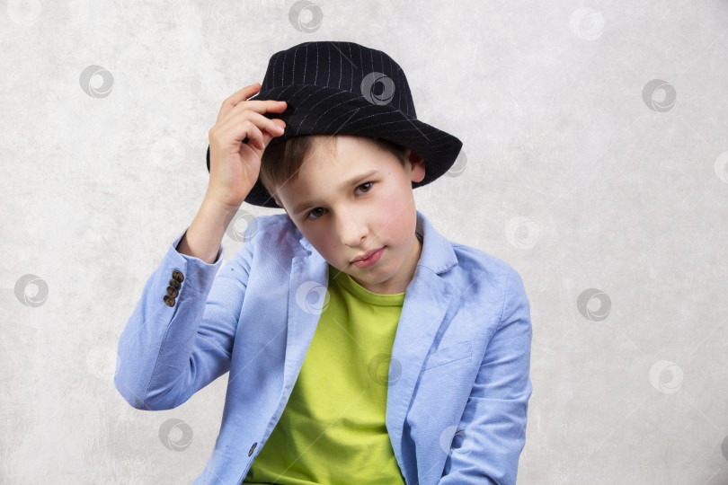 Скачать Элегантный мальчик в костюме и черной шляпе смотрит в камеру. фотосток Ozero