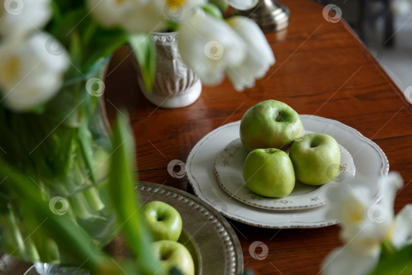 Скачать зеленые яблоки на фарфоровой тарелке на столе фотосток Ozero