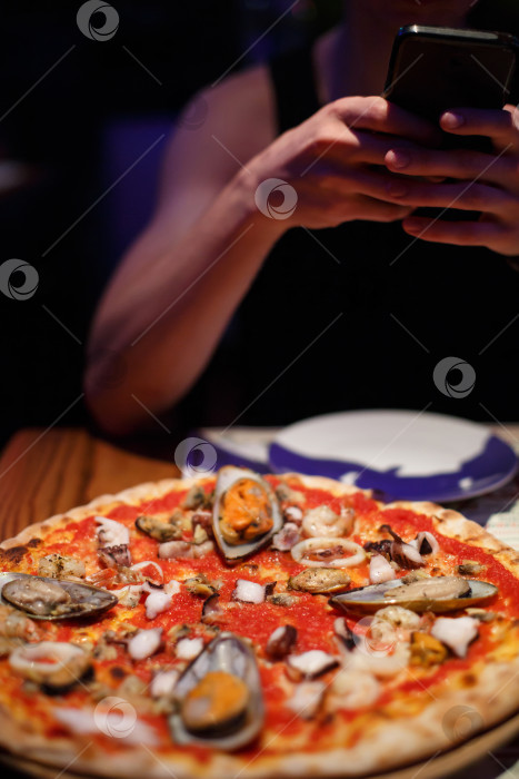 Скачать Мужчина фотографирует пиццу в ресторане или кафе. фотосток Ozero