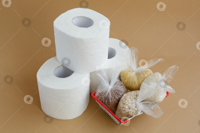 Скачать туалетная бумага и различные крупы в пластиковых пакетах в продуктовой корзине на коричневом фоне фотосток Ozero