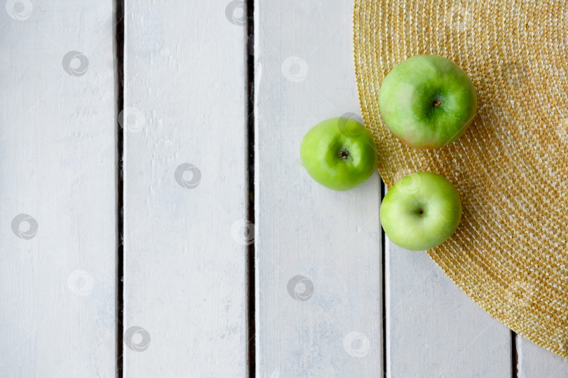 Скачать зеленые яблоки на соломенной шляпе и на фоне деревянных досок фотосток Ozero