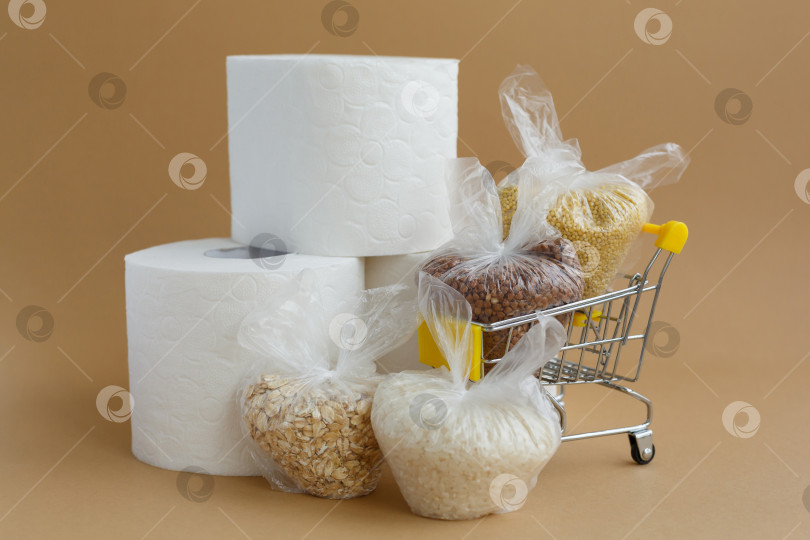 Скачать туалетная бумага и различные крупы в пластиковых пакетах в продуктовой тележке на коричневом фоне фотосток Ozero