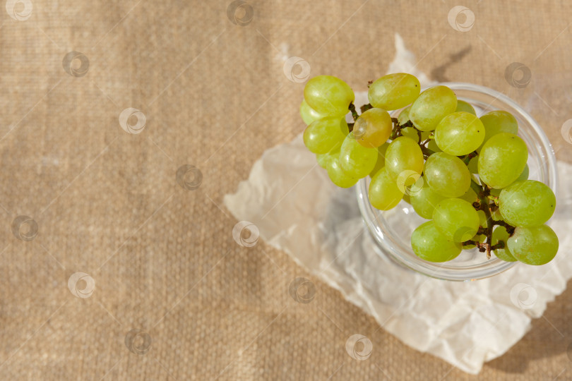 Скачать Плоская поверхность, натюрморт и фотография еды. Блюдо с виноградной гроздью стоит на мешковине фотосток Ozero