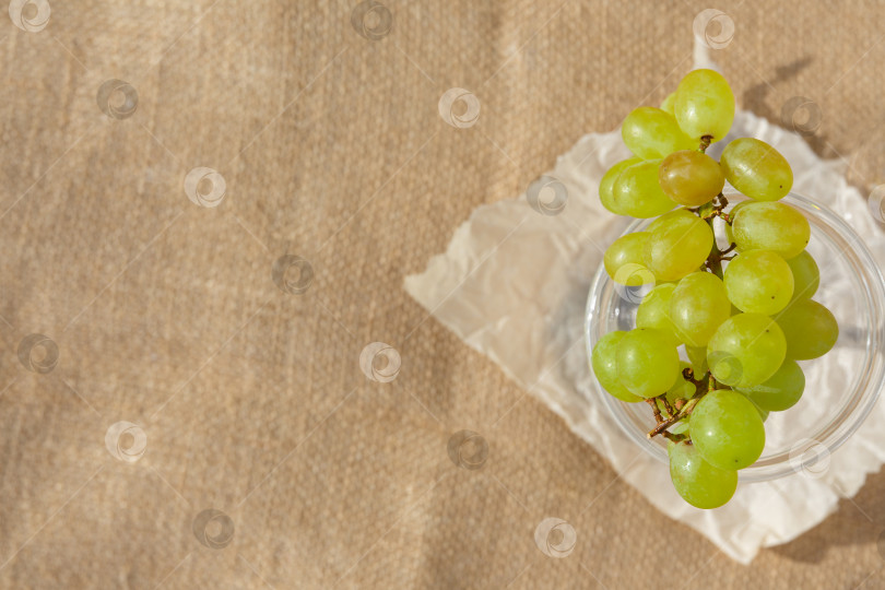 Скачать Плоская поверхность, натюрморт и фотография еды. Блюдо с виноградной гроздью стоит на мешковине фотосток Ozero
