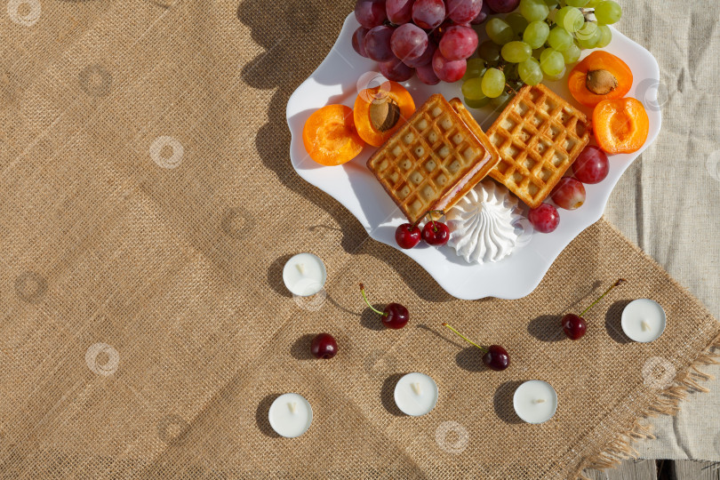 Скачать Плоская поверхность, натюрморт и фотография еды. Тарелка с фруктами и вафлями стоит на мешковине фотосток Ozero