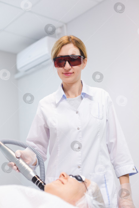 Скачать снимок лица молодой девушки в защитных очках во время процедуры карбонового пилинга в салоне красоты фотосток Ozero