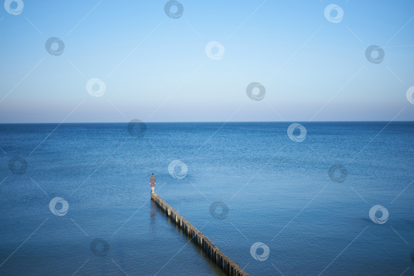 Скачать Одинокая девушка, стоящая на пирсе в море фотосток Ozero
