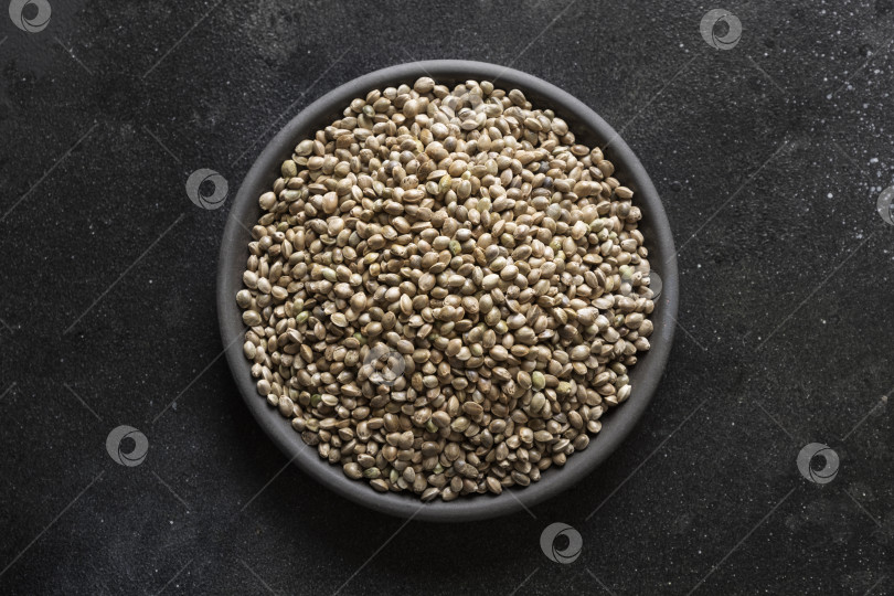 Скачать Органические сушеные семена конопли в черной миске на темном фоне. Вид сверху. фотосток Ozero