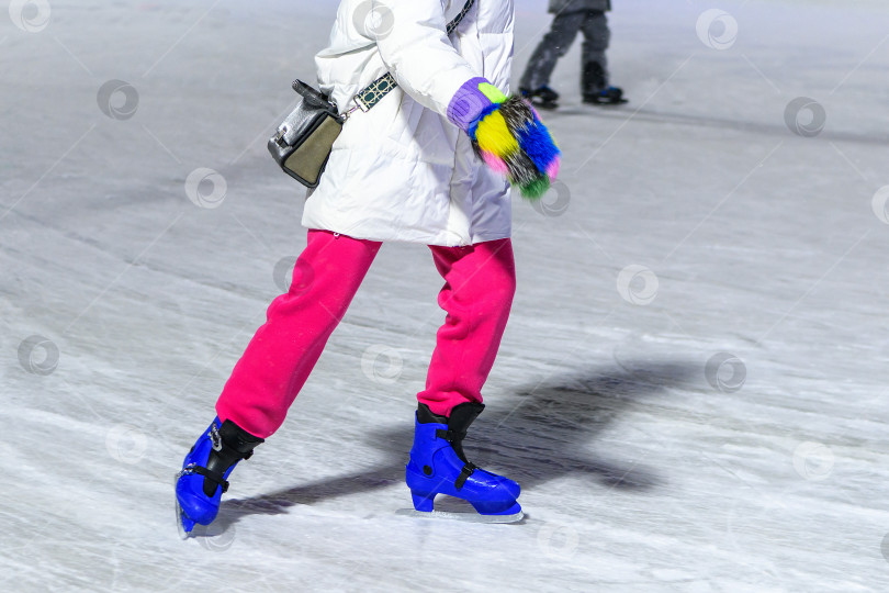 Скачать Крупный план женских ног, катающихся зимой на коньках на открытом катке.Катание на коньках - это весело. фотосток Ozero