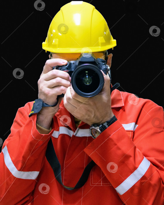Скачать Мужчина-фотограф на строительной площадке в шлеме с зеркальной камерой на черном фоне. Крупный план фотосток Ozero