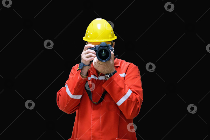 Скачать Фотограф в желтом защитном шлеме и с камерой в руках, выделенный на черном фоне с местом для копирования текста. фотосток Ozero