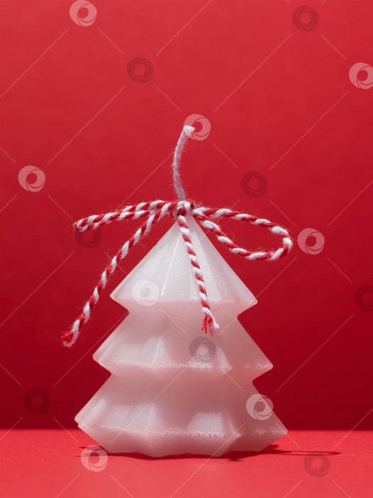 Скачать Одна белая ароматическая свеча в форме рождественской елки на красном фоне фотосток Ozero