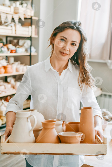 Скачать Женщина-мастер гончарной мастерской несет глиняные изделия для обжига фотосток Ozero