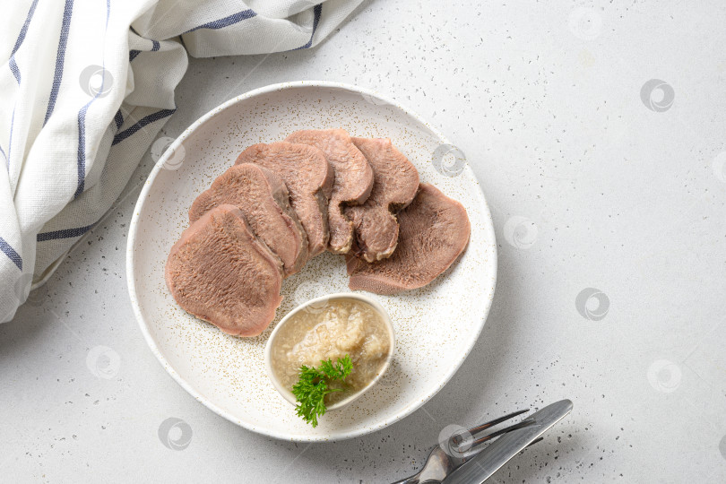 Скачать Деликатесный ломтик говяжьего языка на белой тарелке, красивая классическая подача с натуральным соусом из хрена. фотосток Ozero
