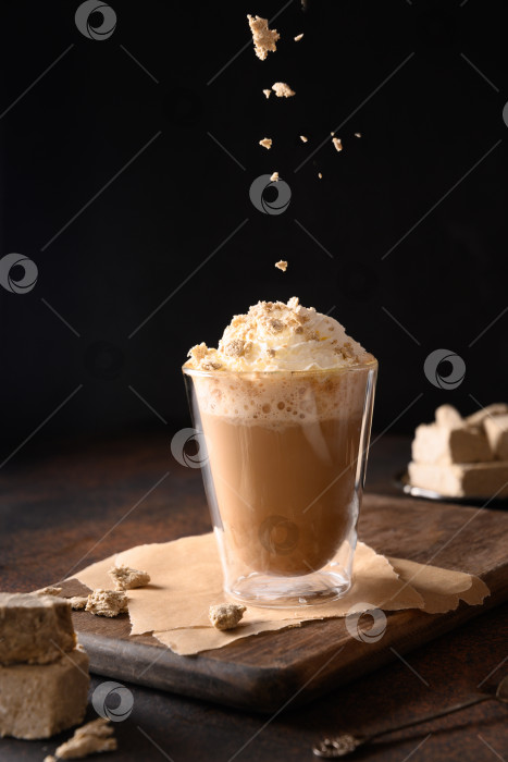 Скачать Посыпает халавой в кофе латте по модному рецепту с халвой в современной стеклянной чашке на темном фоне. фотосток Ozero