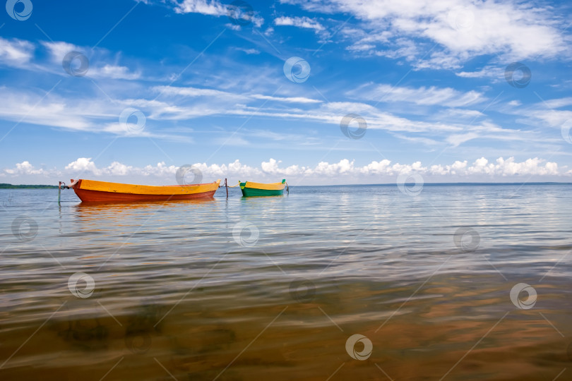 Скачать Красивый пейзаж с лодками на озере и голубым небом с белыми облаками. фотосток Ozero