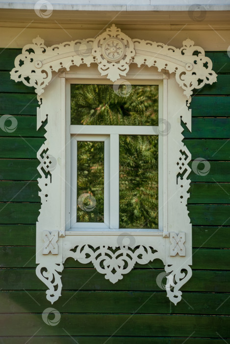 Скачать Окно с деревянной рамой и резными орнаментами на фоне зеленой стены из досок. фотосток Ozero