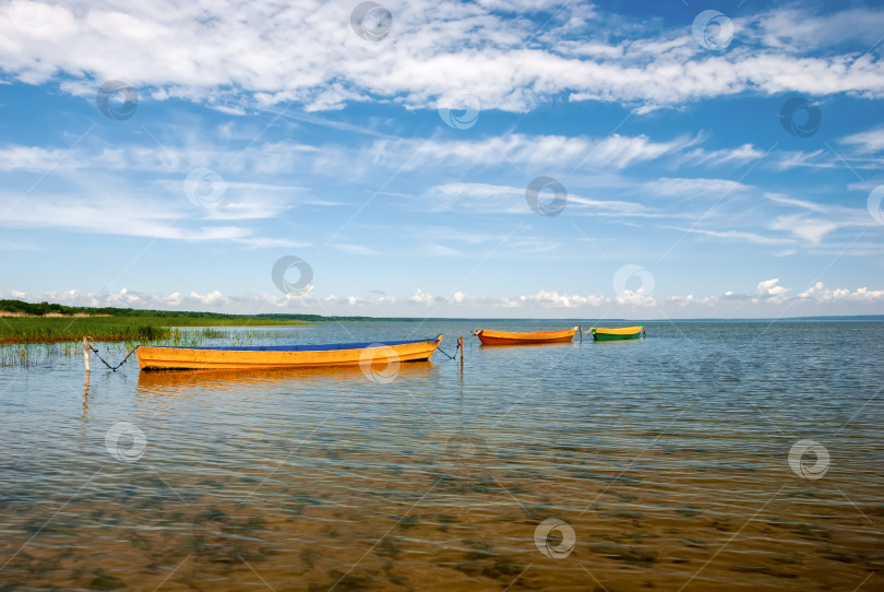 Скачать Красивый пейзаж с лодками на озере и голубым небом с белыми облаками. фотосток Ozero