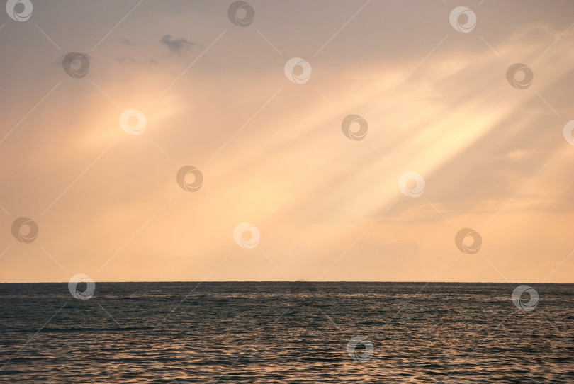 Скачать Лучи солнца пробиваются сквозь облака на гладкую поверхность моря. фотосток Ozero