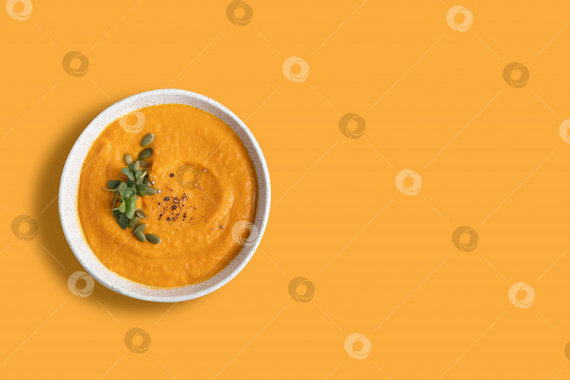 Скачать Тыквенный суп украшен микрозеленью, выделенной на оранжевом фоне. фотосток Ozero