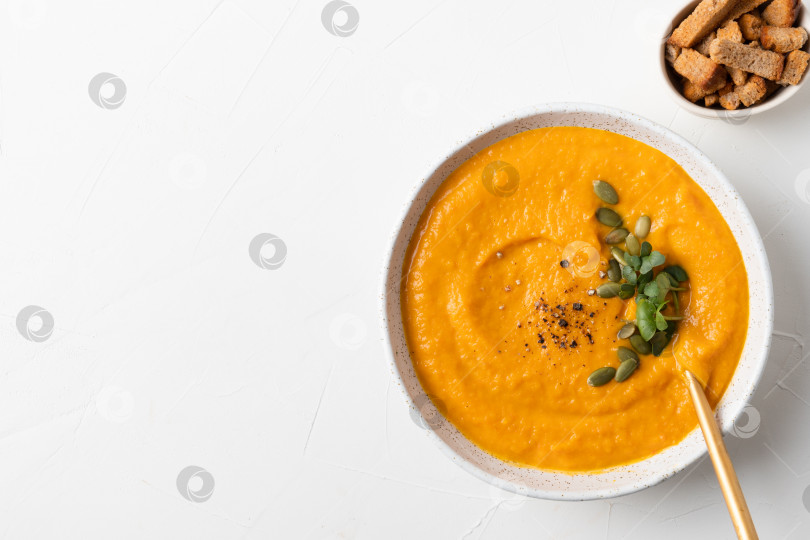 Скачать Осенний тыквенный суп с крекерами на сером фоне. Вид сверху. Место для текста. фотосток Ozero