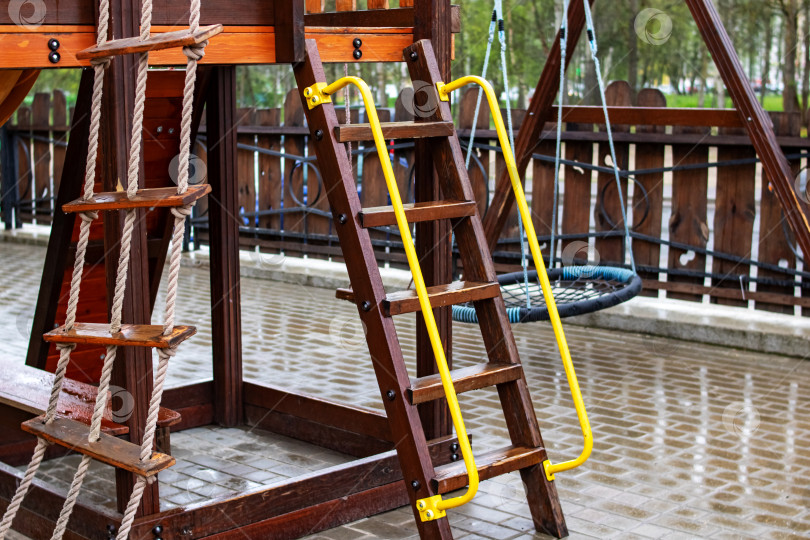 Скачать Деревянная лестница на детской площадке, мокрая под дождем фотосток Ozero