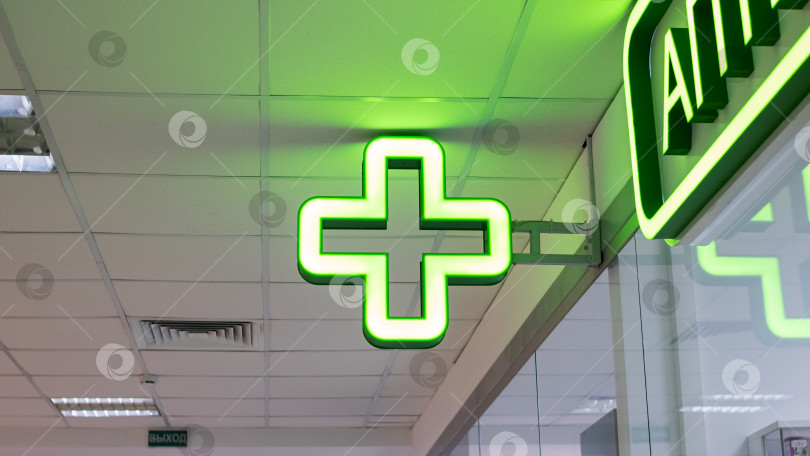 Скачать Лампочка с зеленым крестом в помещении крупным планом, аптечный указатель фотосток Ozero