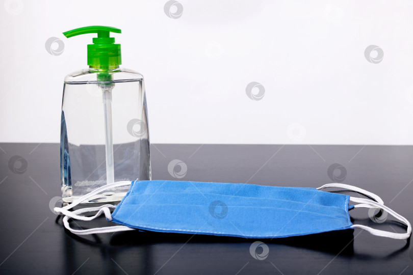 Скачать Флакон с дезинфицирующим средством и медицинскими масками на столе фотосток Ozero