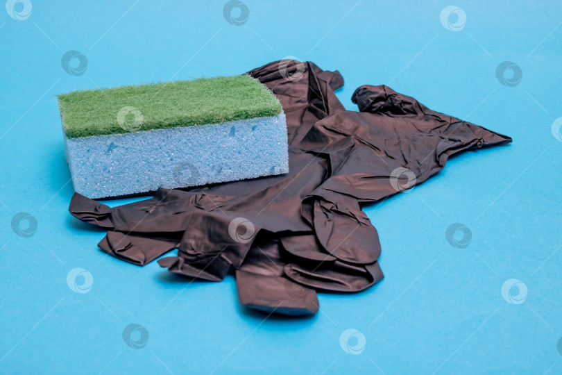 Скачать Черные резиновые перчатки и губка для мытья посуды на синем фоне фотосток Ozero