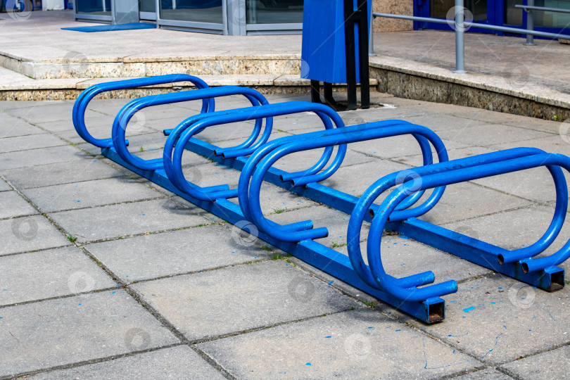 Скачать Синяя пустая металлическая парковка для велосипедов на тротуаре фотосток Ozero