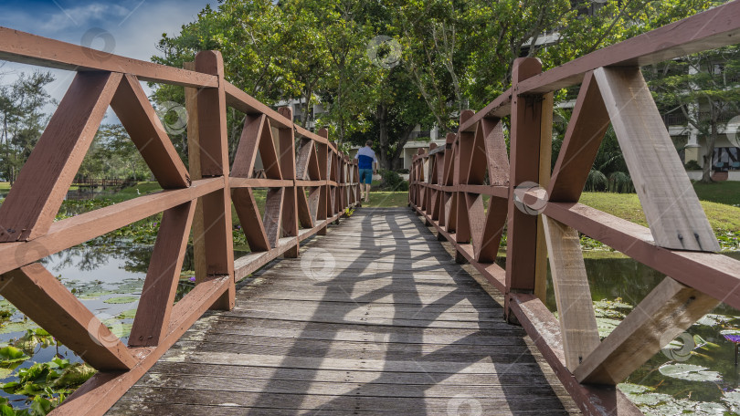 Скачать Через реку перекинут дощатый пешеходный мост с деревянными перилами. фотосток Ozero