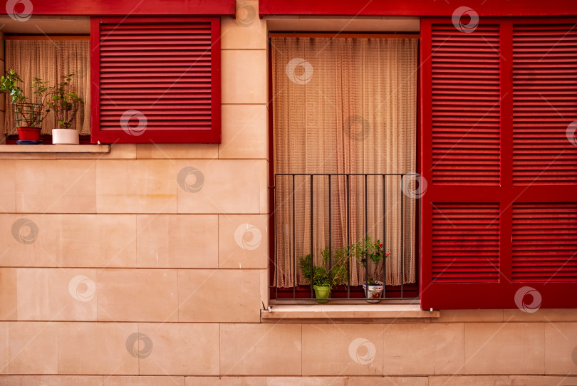 Скачать Деревянное винтажное окно с красными ставнями на оштукатуренной каменной стене в испанском стиле. фотосток Ozero